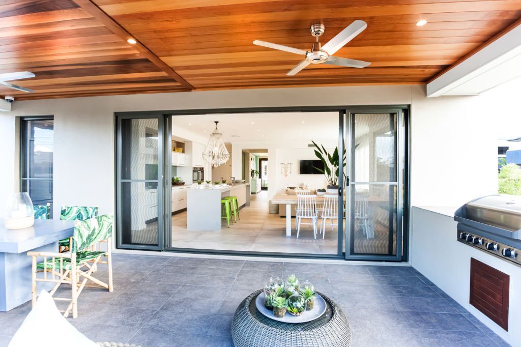 Stylish terrace dining and barbeque décor with contrasting grey furniture with green chairs and planters for centre table.